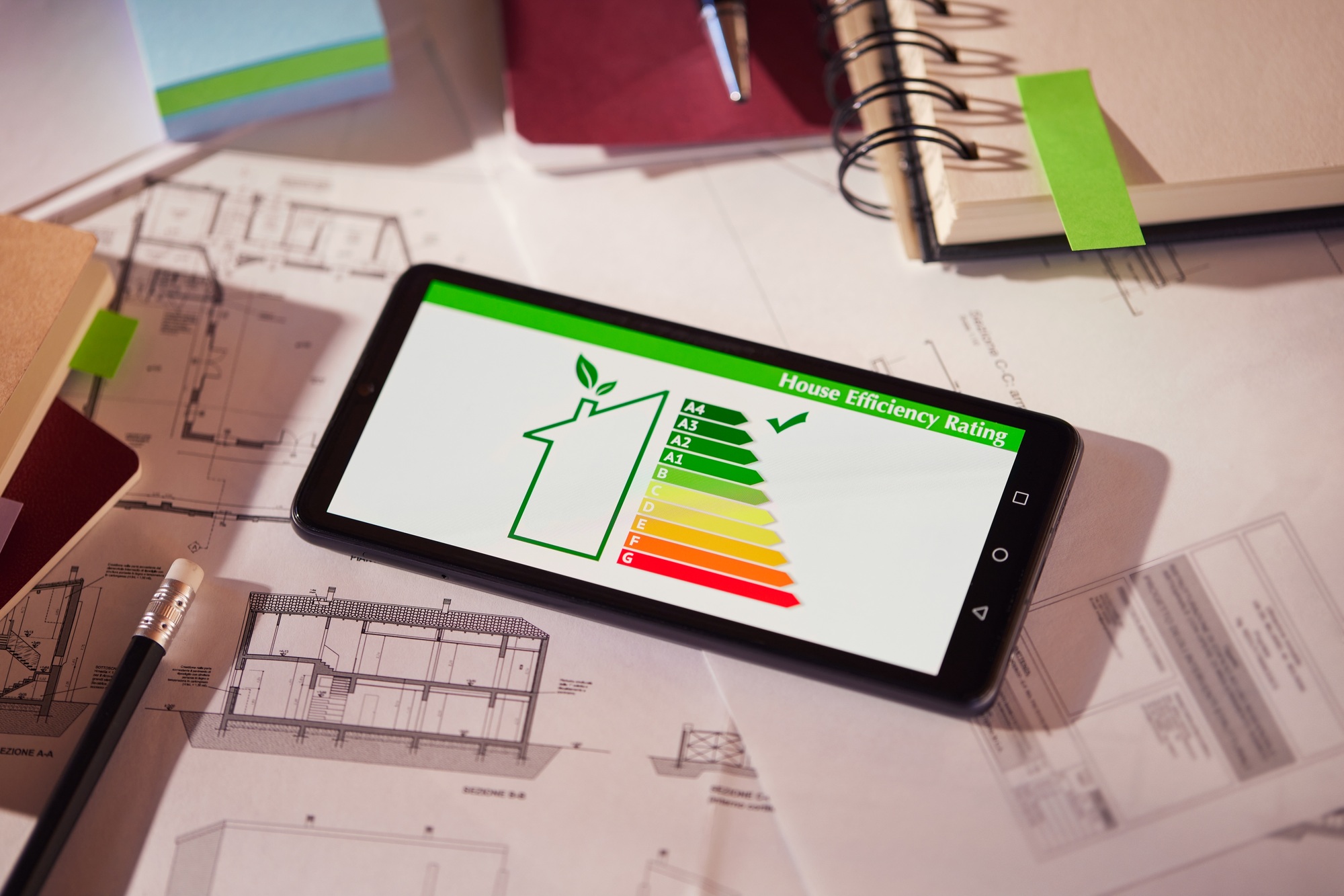 Energy class and efficiency app on phone over architectural plans